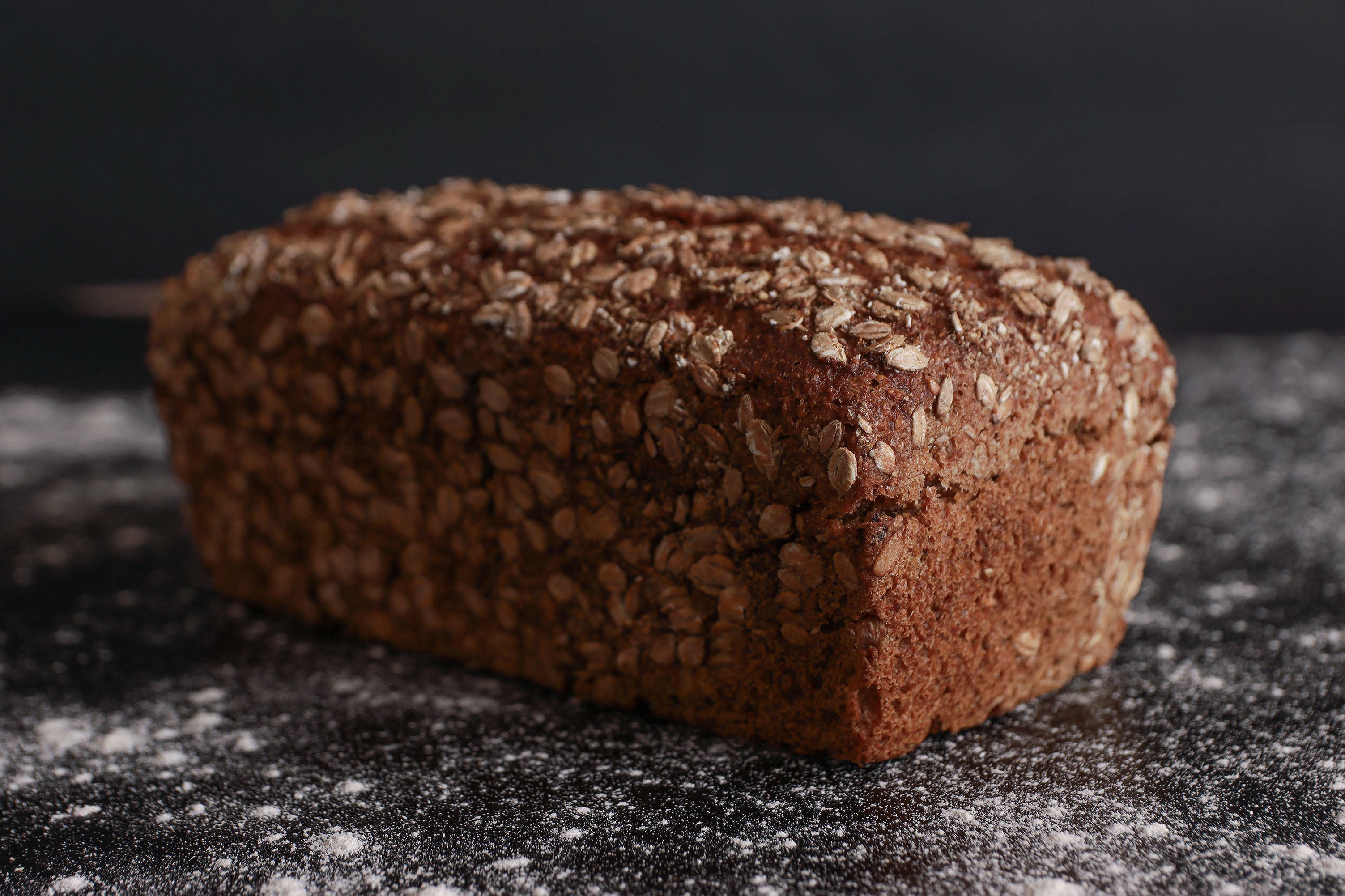 Ein Laib Dinkelbrot in einer Kastenform, bestreut mit Dinkelflocken. Gebacken von Hand und in Bio-Qualität in der antonius Bäckerei.