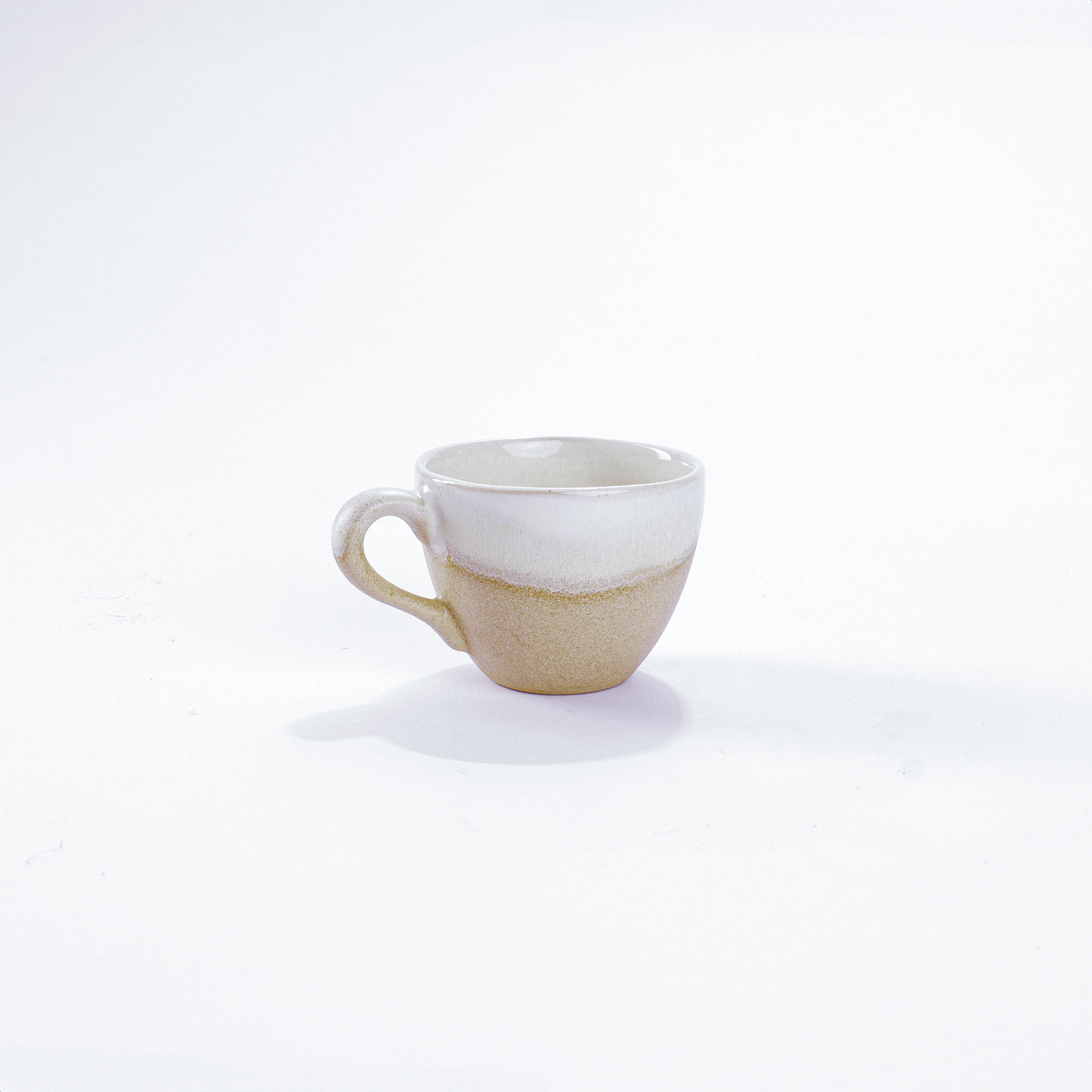 Unsere Keramik Espressotasse in der Farbe Basaltweiß aus Steinzeug-Keramik, mit einer Kapazität von 60 Milliliter, einem Durchmesser von 6,5 Zentimeter und einer Höhe von 5 Zentimeter. Aus unserer nachhaltigen Töpferei selbst getöpfert und mit handaufgetragener Glasur gebrannt.