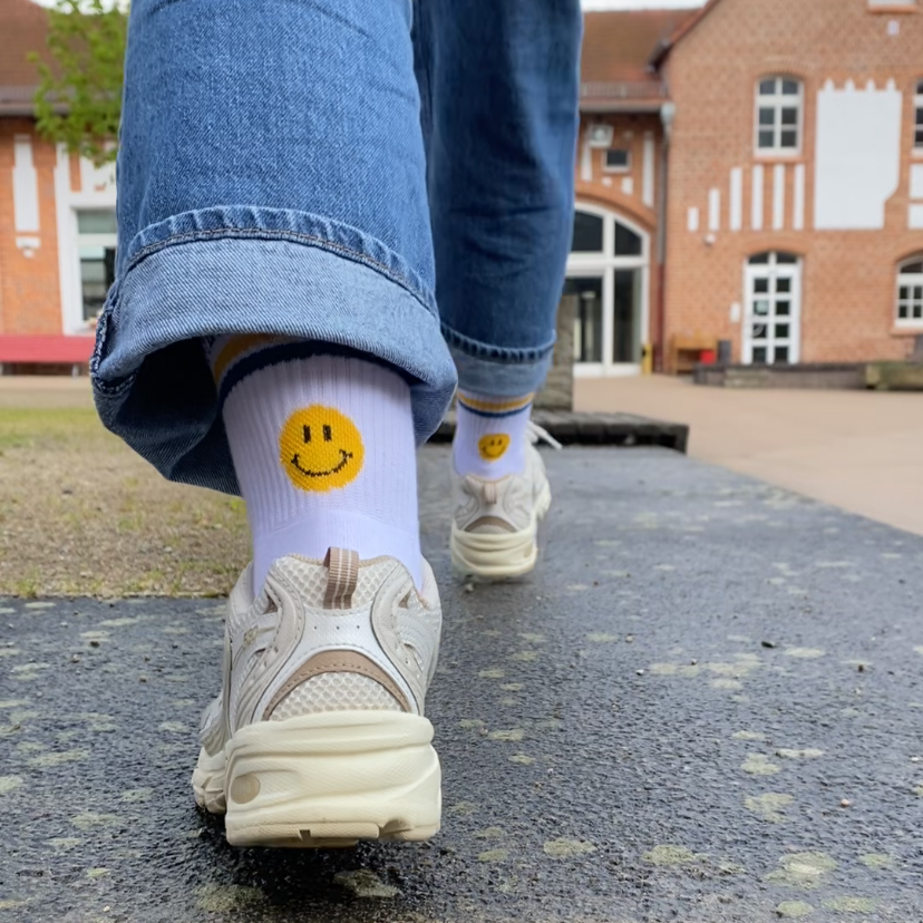 Die Gude Socke von hinten. Es ist ein gelber Smiley unter den Streifen zu sehen.