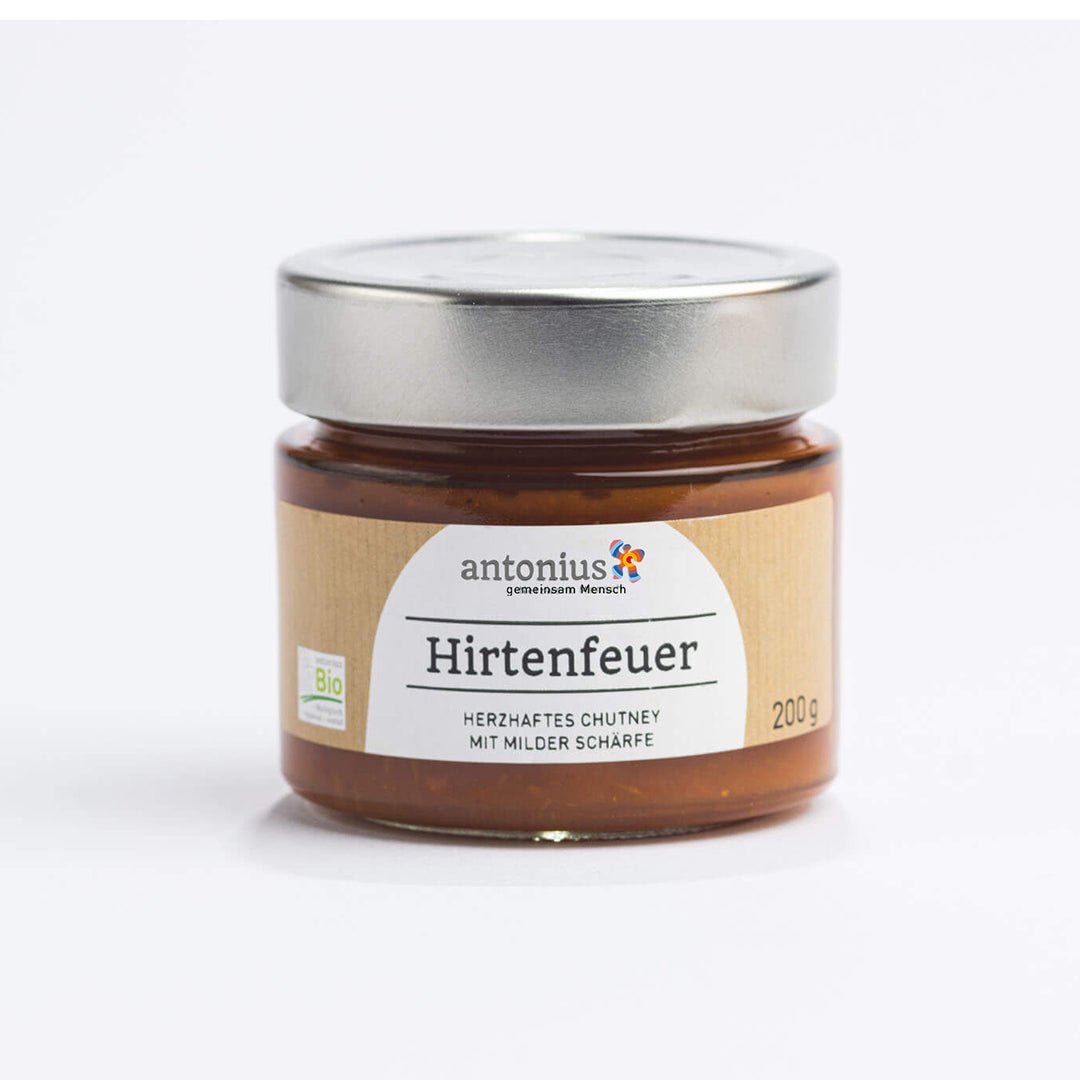 Ein mit einem Metalldeckel verschlossenes Glas mit Hirtenfeuer-Chutney. Auf dem Etikett sind Informationen zur Füllmenge und die Aufschrift "Hirtenfeuer - Herzhaftes Chutney mit milder Schärfe"