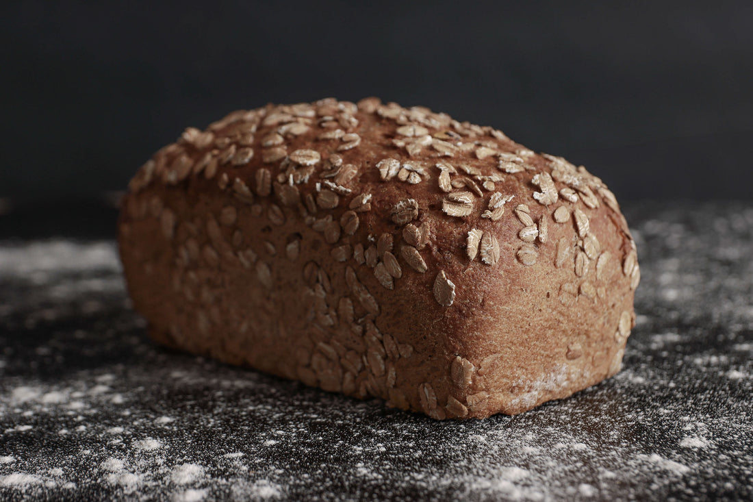 Ein Laib Roggenvollkornbrot in einer Kastenform, bestreut mit Roggenflocken. Gebacken von Hand und in Bio-Qualität in der antonius Bäckerei.