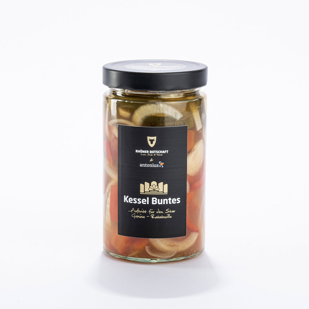 Ein durchsichtiges Einmachglas ist gefüllt mit verschiedenem Gemüse - man erkennt Tomaten, Zwiebeln und Zucchini - und verschlossen mit einem schwarzen Metalldeckel. Auf dem schwarzen Etikett steht &quot;Kessel Buntes ... Auftritt für den Star, Gemüse-Ratatouille&quot;.
