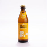Eine Flasche vom hauseigenen Bio-Bier Frauenberger Frohnatur. Eine braune Glasflasche, verschlossen mit einem goldenen Kronkorken, mit der Füllmenge 0,33l und einem gelben Etikett. Darauf am Flaschenhals die Aufschrift Fuldaer Spezialitäten. Unten Frauenberger Frohnatur - Bio Helles Bier.