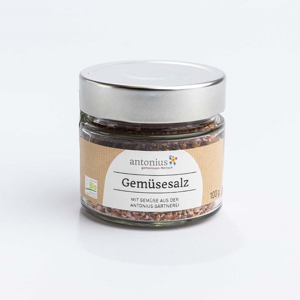 Ein Glas mit Metalldeckel, gefüllt mit Bio-Gemüsesalz aus Karotten, Pastinaken und Roter Bete. Auf dem Etikett steht: "Gemsesalz mit Gemüse aus der antonius Gärtnerei". Das Glas umfasst 100 Gramm.