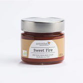 Ein mit einem Metalldeckel verschlossenes Glas mit Sweet Fire-Chutney in Bio-Qualität. Auf dem Etikett sind Informationen zur Füllmenge und die Aufschrift "Sweet Fire - Erst süß, dann sehr scharf - feuriges Chutney"