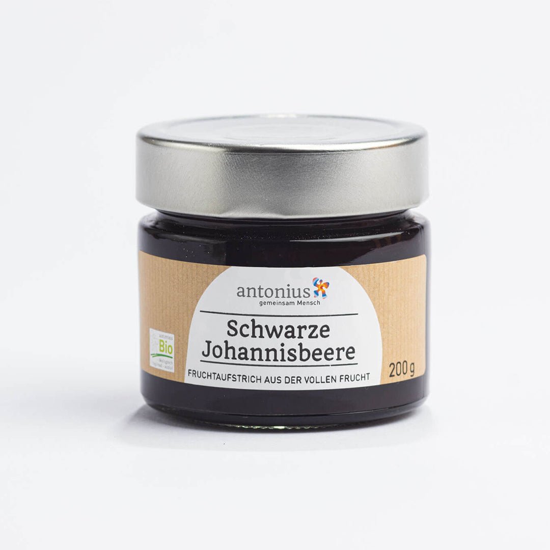 Ein mit einem Metalldeckel verschlossenes Glas mit Schwarze Johannisbeere-Fruchtaufstrich und der Aufschrift &quot;Fruchtaufstrich aus der vollen Frucht&quot;.
