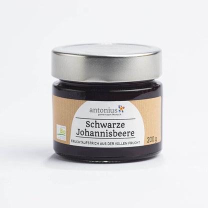 Ein mit einem Metalldeckel verschlossenes Glas mit Schwarze Johannisbeere-Fruchtaufstrich und der Aufschrift &quot;Fruchtaufstrich aus der vollen Frucht&quot;.