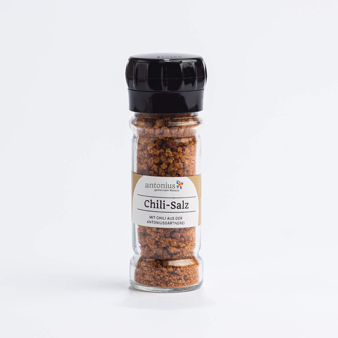 Ein Gewürzstreuer, gefüllt mit Chili-Salz. Auf dem Etikett steht: "Chili-Salz mit Chili aus der antonius Gärtnerei".
